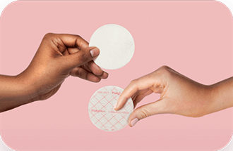 Two hands holding Nursicare Therapeutic Breast Pads over a pink background.